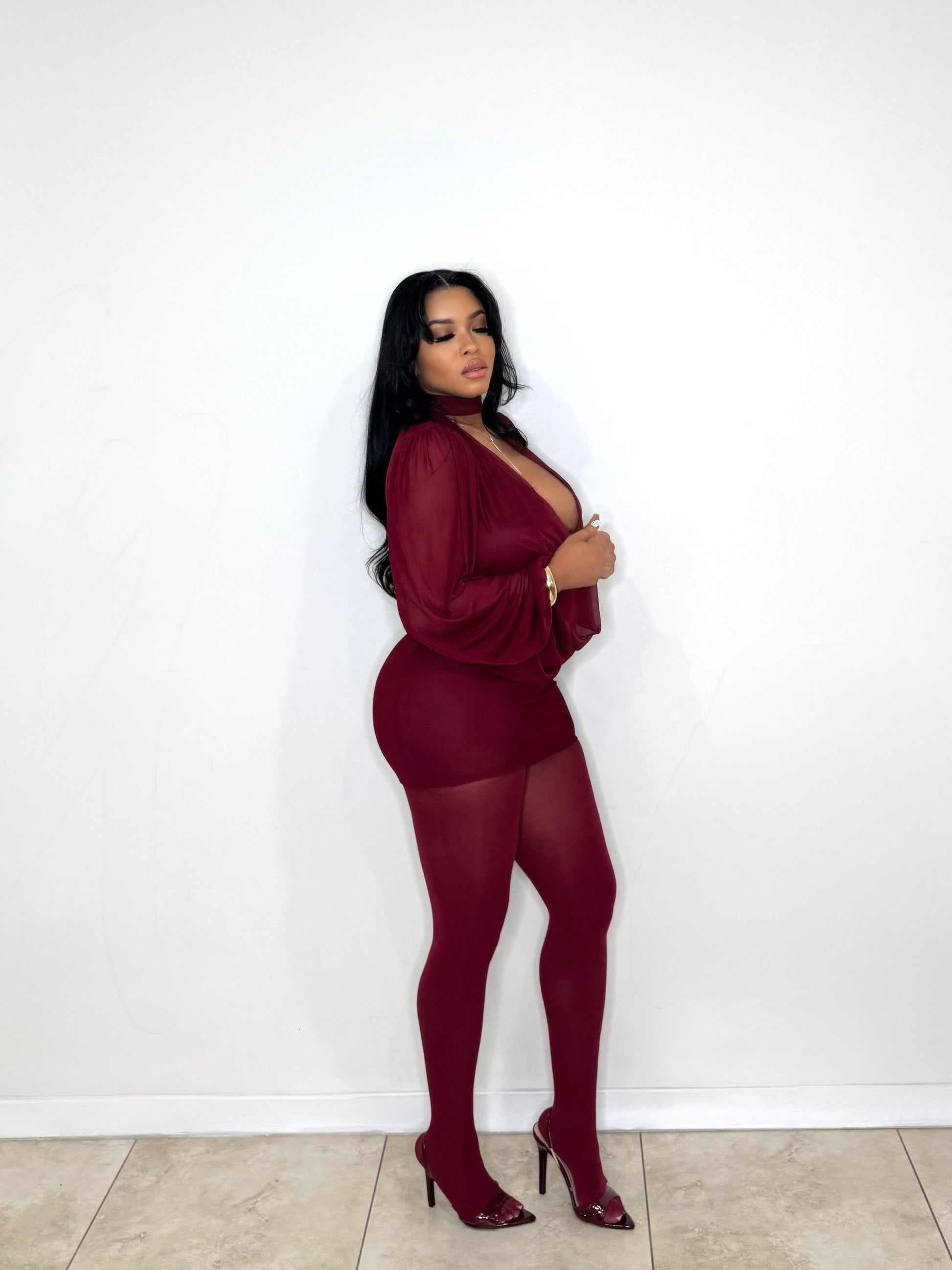 Woman wearing a burgundy outfit against a white wall